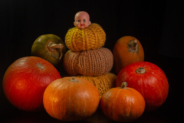 Yellow-orange pumpkins with broken cracked doll head candles and skulls on a black background the concept of Halloween and the autumn harvest of pumpkin close-up copyspace from above