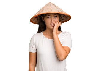 Young asian woman wearing a Vietnamese hat isolated biting fingernails, nervous and very anxious.