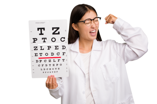 Young asian oculist woman holding a eye chart paper isolated raising fist after a victory, winner concept.