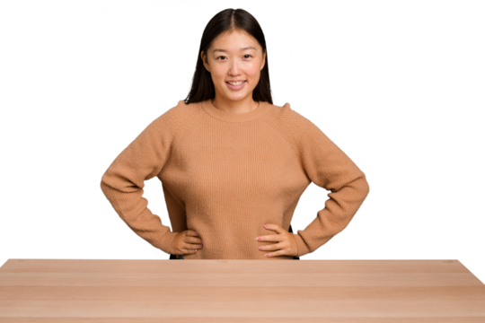 Young asian woman sitting on a table isolated confident keeping hands on hips.