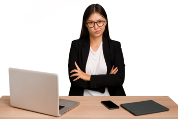 Young business asian woman sitting on a table isolated unhappy looking in camera with sarcastic expression.