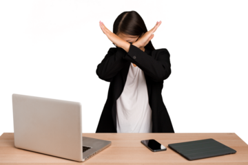 Young business asian woman sitting on a table isolated keeping two arms crossed, denial concept.