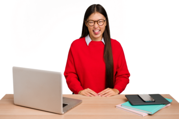 Young student asian woman in a workplace with a laptop isolated funny and friendly sticking out tongue.