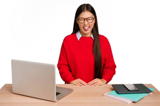 Young student asian woman in a workplace with a laptop isolated funny and friendly sticking out tongue.
