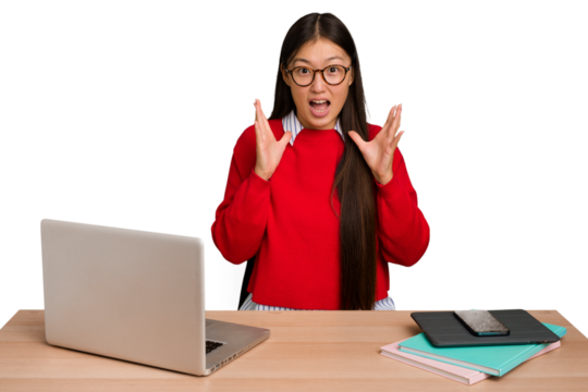Young student asian woman in a workplace with a laptop isolated screaming to the sky, looking up, frustrated.