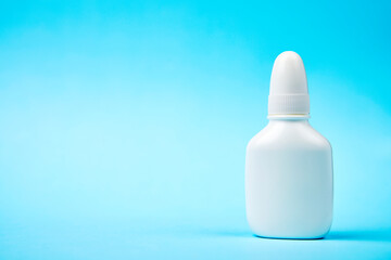Nasal spray bottle on blue background with copy space
