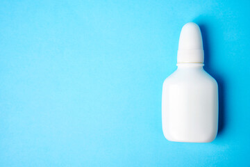Nasal spray bottle on blue background with copy space