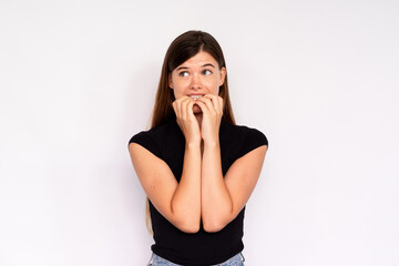 Portrait of neurotic young woman biting nails over white background. Caucasian lady wearing black...