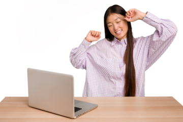 Young student asian woman in a workplace with a laptop isolated celebrating a special day, jumps and raise arms with energy.