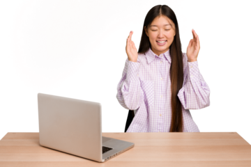Young student asian woman in a workplace with a laptop isolated joyful laughing a lot. Happiness concept.