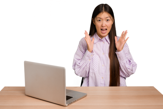 Young student asian woman in a workplace with a laptop isolated screaming to the sky, looking up, frustrated.