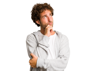 Young curly smart caucasian man cut out isolated relaxed thinking about something looking at a copy space.
