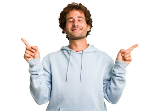 Young curly smart caucasian man cut out isolated pointing to different copy spaces, choosing one of them, showing with finger.