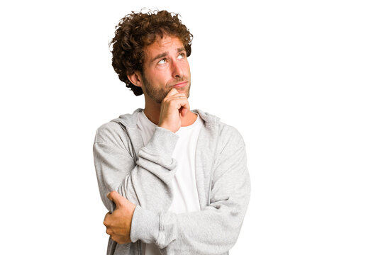 Young curly smart caucasian man cut out isolated relaxed thinking about something looking at a copy space.