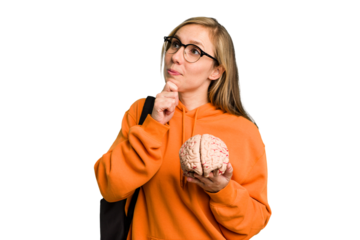 Young student caucasian woman holding a brain isolated looking sideways with doubtful and skeptical expression.