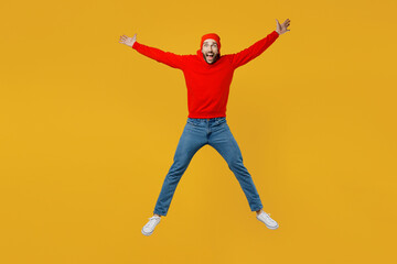 Fototapeta na wymiar Full body exultant young caucasian man wear red hoody hat look camera jump high with outstretched arms hands scream isolated on plain yellow color background studio portrait. People lifestyle concept.