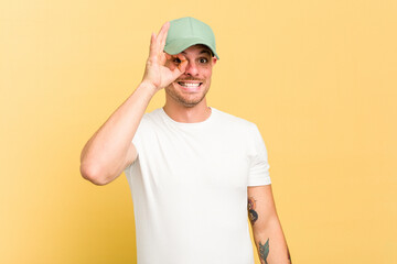 Young caucasian handsome man isolated on yellow background excited keeping ok gesture on eye.