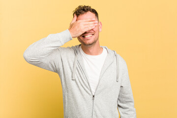 Young caucasian handsome man isolated on yellow background covers eyes with hands, smiles broadly waiting for a surprise.