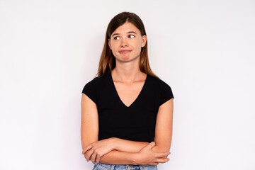 Portrait of young woman looking away with scorn over white background. Caucasian lady wearing black T-shirt and jeans standing with folded arms. Mistrust concept - obrazy, fototapety, plakaty
