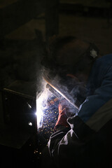 A worker welding metal parts on a construction site. A welder welds parts of a large machine in a metallurgical workshop.. An interesting example of manual work.	