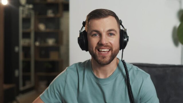 A young man in headphones greets and talks on a video call