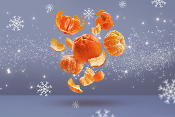 Peeled and whole tangerines fly in the air against the background of snowflakes. Winter composition. Food levitation.
