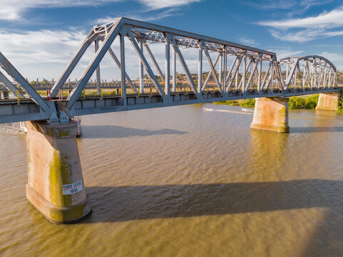 Aerial view of a steel bridge crossing a wide brown river