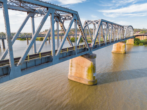 Aerial view of a steel span bridge crossing a wide brown river