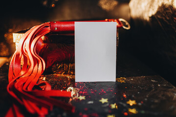 card mockup, mockup of a white sheet of paper bdsm toys, red leather whip on a black background...
