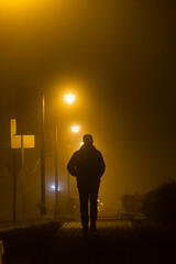 Solomons Island, Maryland, USA A man walks alone in silhouette on a narrow brick sidewalk at night...