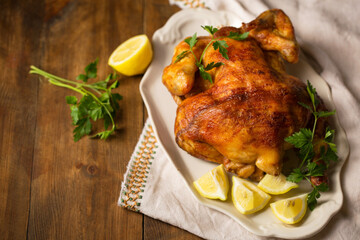 A whole ruddy baked chicken with lemon on a plate