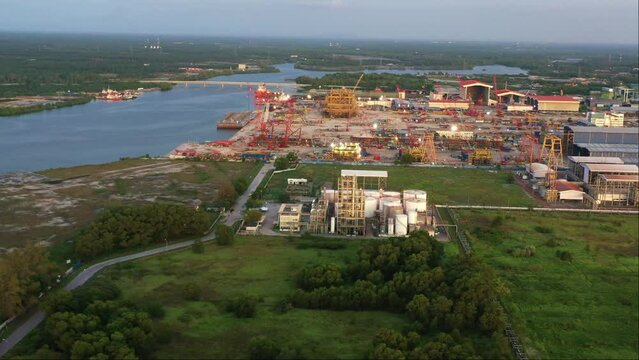 Aerial panning shot capturing massive fabrication yard, plant and marine shipyard at Kampung Acheh Lumut port industrial park, ship building and repair hangars and hardstands, Perak, Malaysia.