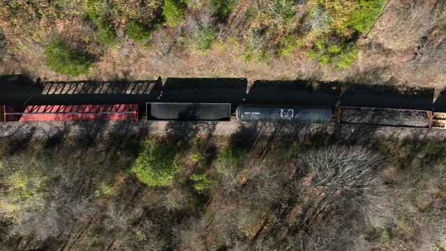 Top down aerial of train car carrying coal on track. Golden hour shadow. Top down aerial view.