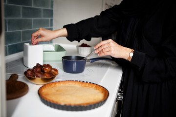 Woman cooks pie on stove. Hands close up