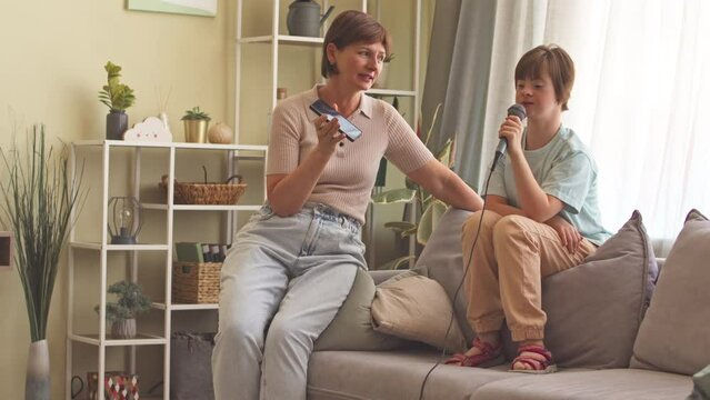 Talented 14 year old girl with down syndrome singing in microphone with mother at home