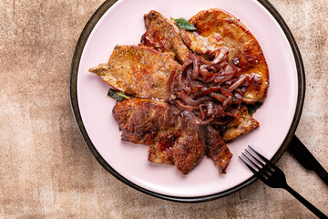 Top view of plate with fried beef liver with caramelized onions, garlic and sage.