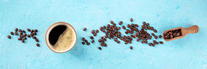 Coffee cup and beans panorama, overhead flat lay shot on a blue background with copy space, a panoramic banner for a menu