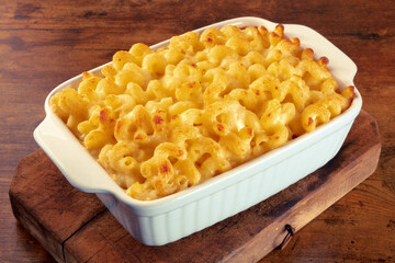 Macaroni and cheese pasta in a casserole on a rustic background, a cheesy American dish with noodles and Cheddar