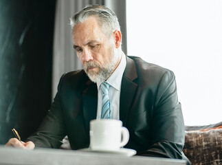 Business person sign agreement contract with pen in hand at corporate office. Businessman holding pen signing paper document finance deal for legal contract. Success business negotiation signature.