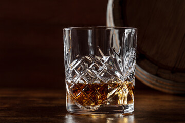 Whiskey in a glass with a barrel. Bourbon whisky and a cask on a dark rustic wooden background