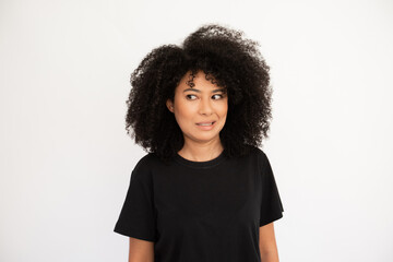 Dissatisfied young woman showing irritation. Hispanic female model with afro hairstyle and brown eyes in black T-shirt making irritated facial expression. Emotion, dissatisfaction concept