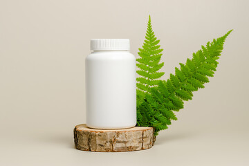 Mockup vitamin bottle on wooden stand with fern leaves, natural bio supplement, herbal medical...