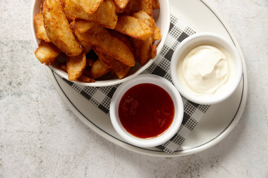 Close up of bowl of wedges with sweet chilli and sour cream on the side