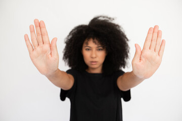 Close-up of stop signs made by serious young woman. Caucasian female model with afro hairstyle and...