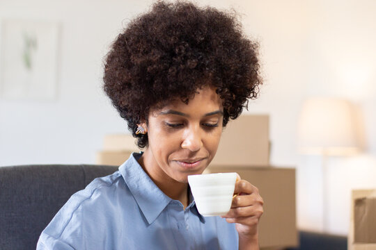 Smiling Woman With Afro Hairstyle In Office. Content Attractive Black Postal Worker Drinking Espresso And Looking Down. Supervisor Concept