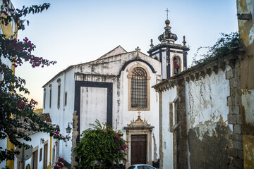 Narrow cobblestone streets, historic white houses covered with ceramic tiles, townhouses and the castle of the town of Obidos.