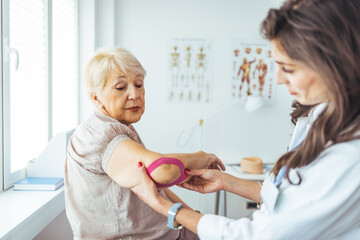 Fototapeta premium Female doctor chiropractor or osteopath fixing womans shoulder with hands movements during visit in manual therapy clinic. Support for strained muscles. Physical therapy diagnosing concept
