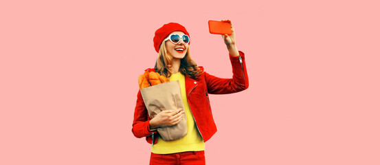 Portrait stylish happy smiling young woman taking selfie with smartphone holding grocery shopping...