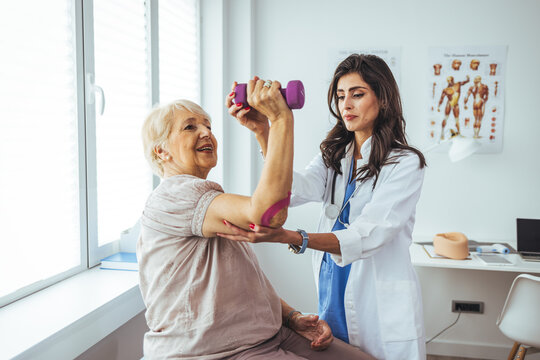 Physiotherapist woman giving exercise with dumbbell treatment About Arm and Shoulder of senior female patient Physical therapy concept. Physiotherapist assisting female patient