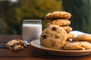 Pile of chocolate cookies with a glass of milk on a wooden table